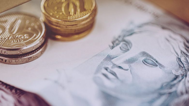Tipos de títulos de capitalização: Dinheiro brasileiro em close-up. Nota de cem reais e moedas brasileiras, conceito de economia.