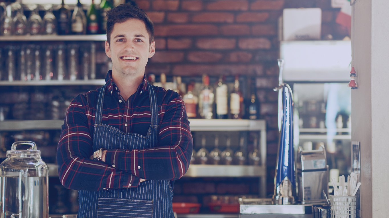 Franquias até 50 mil reais: Retrato de um jovem empresário sorridente em um pequeno restaurante