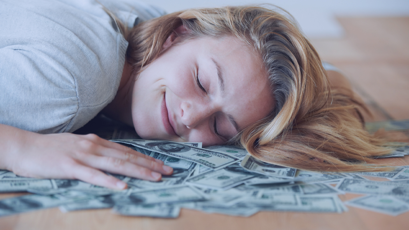 Loteria mais fácil de ganhar: Mulher feliz deitada em cima de muito dinheiro