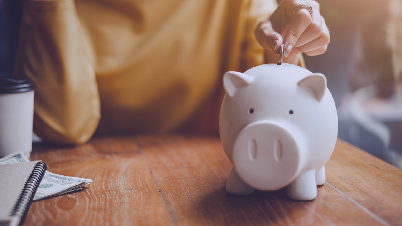 mão de mulher colocando moedas de dinheiro no porquinho para economizar dinheiro, riqueza e conceito financeiro.