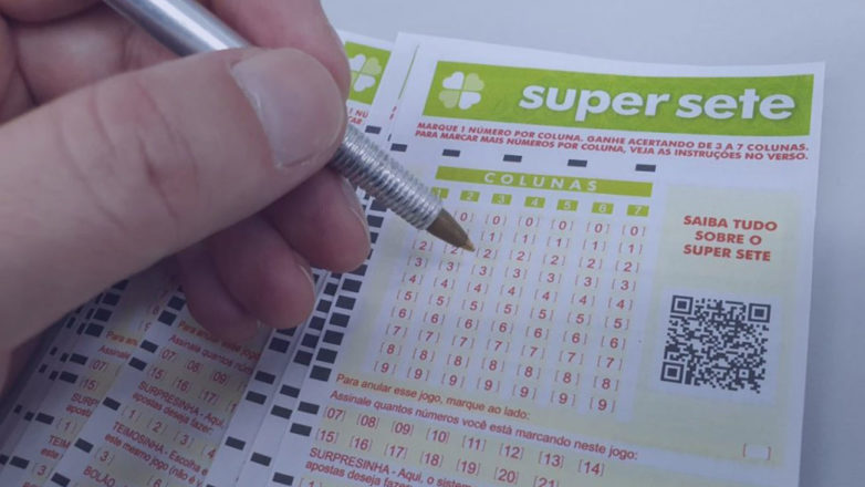 Pessoa marcando os números com uma caneta em um cartão de loteria