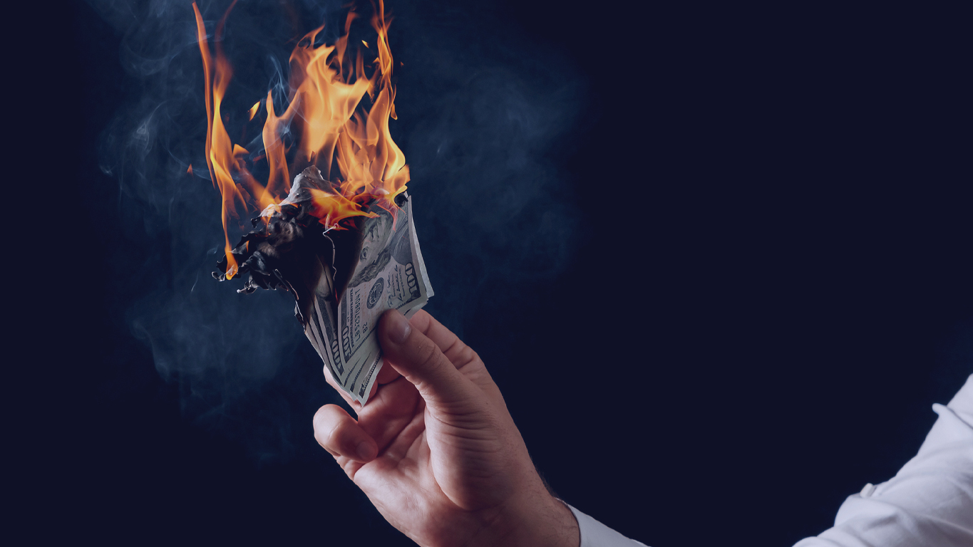 Sonhar com dinheiro falso: Pessoa segurando nota de dólar pegando fogo