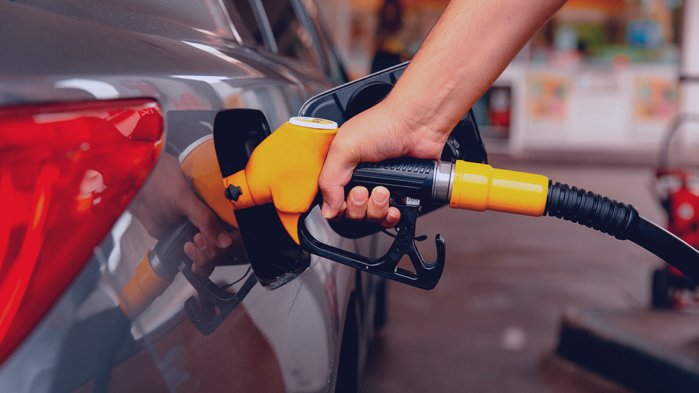 Mão de homem enchendo o combustível do carro em tanque de posto de gasolina de autoatendimento.