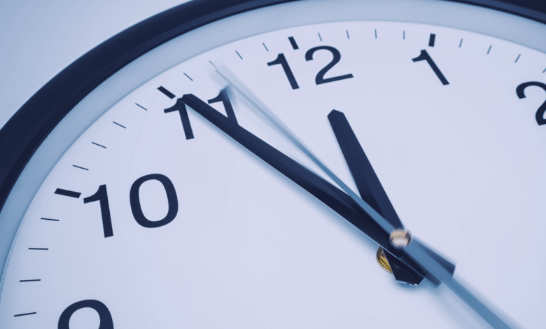 relógio análogico de parede mostrando 5min antes das 12 horas