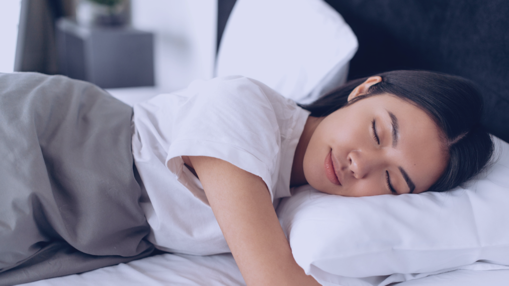 Sonhar com números de loteria. Vista lateral de uma garota asiática dormindo em uma cama.