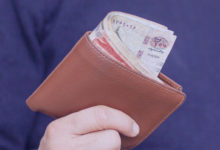 Homem segurando carteira com dinheiro a amostra