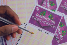 cartela da lotofacil da independencia com uma mão segurando uma caneta e marcando as apostas