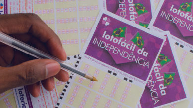 cartela da lotofacil da independencia com uma mão segurando uma caneta e marcando as apostas