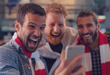 3 homens se divertindo olhando para um celular.