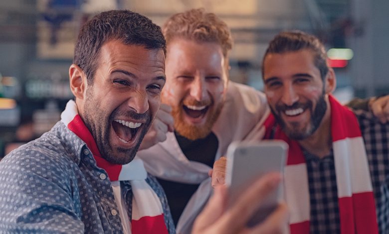 3 homens se divertindo olhando para um celular.