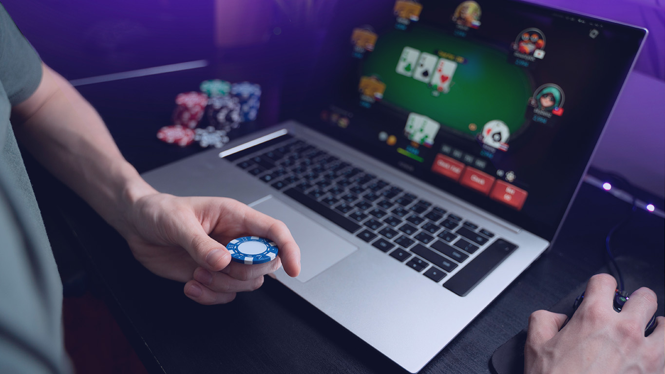 Imagem de um laptop com um jogo de cassino e mãos masculinas ao redor.