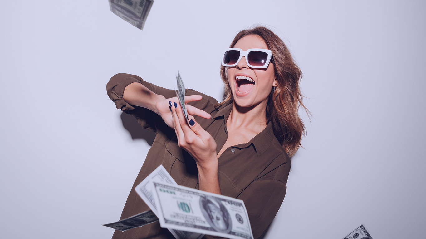 Mulher de óculos escuros, jogando dinheiro pelo ar.